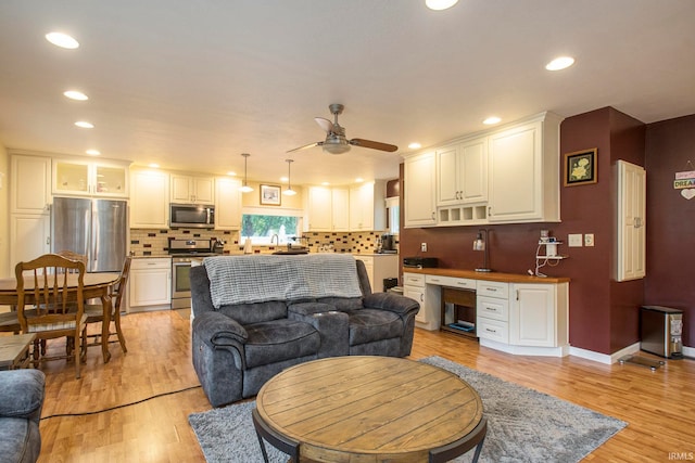 living room featuring built in desk, light hardwood / wood-style floors, and ceiling fan