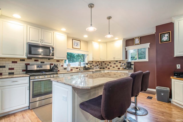 kitchen featuring a wealth of natural light, a kitchen breakfast bar, appliances with stainless steel finishes, and a kitchen island