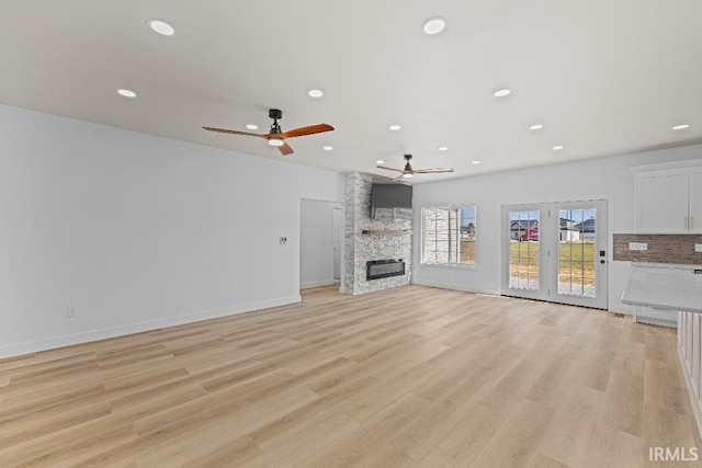 unfurnished living room featuring light hardwood / wood-style floors, a fireplace, and ceiling fan