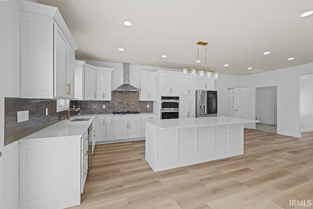 kitchen with wall chimney exhaust hood, a center island, stainless steel appliances, and white cabinets