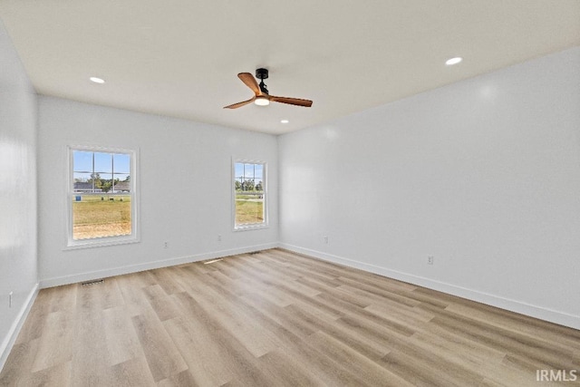 empty room featuring light wood-type flooring, a healthy amount of sunlight, and ceiling fan