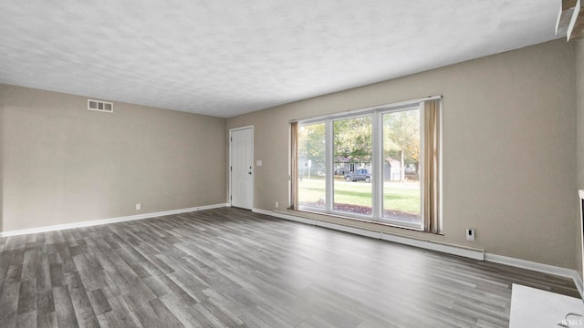 spare room featuring a baseboard heating unit, a textured ceiling, and wood-type flooring