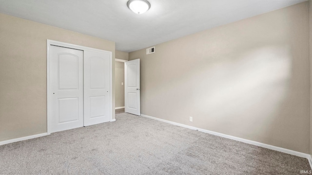 unfurnished bedroom featuring light colored carpet and a closet