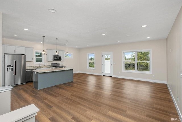 kitchen featuring appliances with stainless steel finishes, a center island, hanging light fixtures, white cabinetry, and dark hardwood / wood-style floors