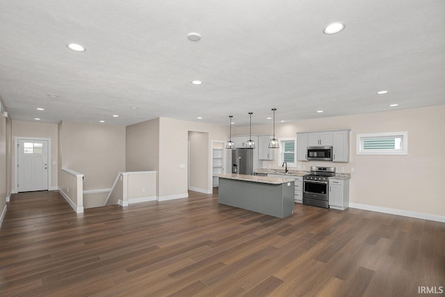 kitchen with appliances with stainless steel finishes, sink, a center island, hanging light fixtures, and dark hardwood / wood-style floors