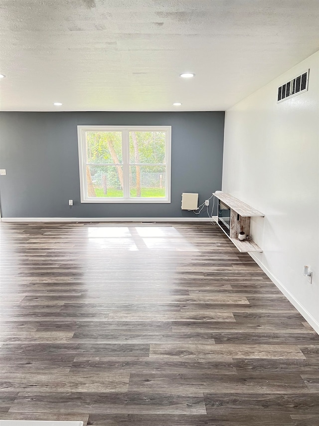 unfurnished room featuring a textured ceiling and dark hardwood / wood-style flooring