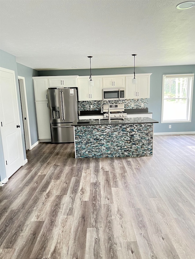 kitchen featuring sink, decorative light fixtures, white cabinetry, appliances with stainless steel finishes, and tasteful backsplash