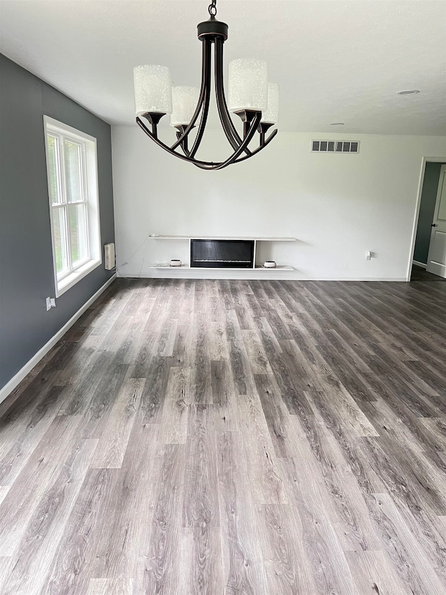 unfurnished living room featuring wood-type flooring and a chandelier