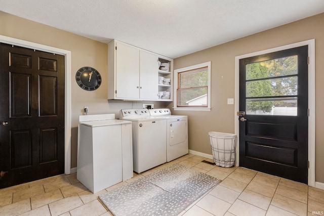 laundry area with cabinets, independent washer and dryer, a textured ceiling, and light tile patterned flooring