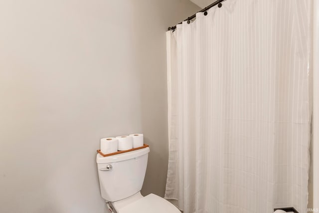 bathroom with a shower with shower curtain and toilet