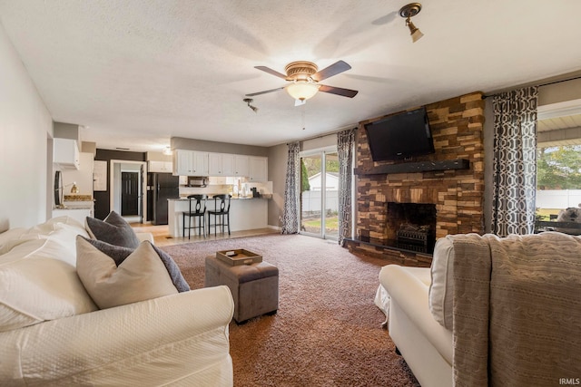 carpeted living room featuring ceiling fan, a textured ceiling, and a fireplace