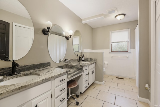 2324 W 56th Hwy, Scottsburg, IN 47170 - bathroom with double vanity, wainscoting, toilet, tile walls, and a sink