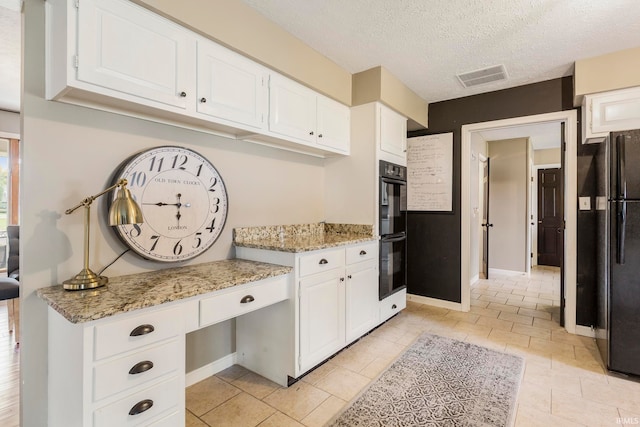 kitchen featuring black appliances, light stone countertops, a textured ceiling, and white cabinets