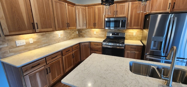 kitchen with light stone countertops, decorative backsplash, stainless steel appliances, and sink