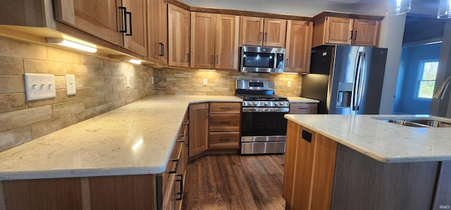 kitchen featuring sink, dark wood-type flooring, stainless steel appliances, light stone counters, and decorative backsplash