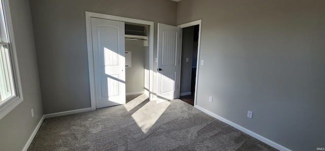 unfurnished bedroom featuring dark carpet and a closet