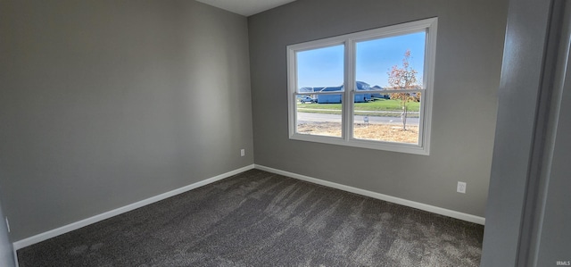 spare room featuring dark colored carpet