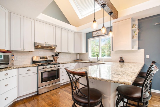 kitchen with dark hardwood / wood-style floors, white cabinetry, stainless steel appliances, and a breakfast bar area