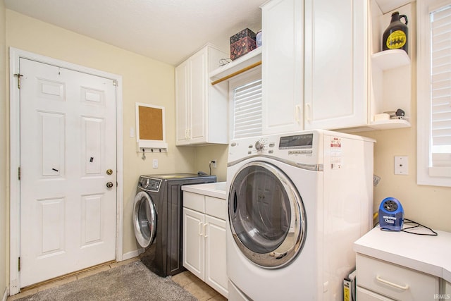 laundry room featuring washer and dryer, a textured ceiling, light tile patterned floors, and cabinets