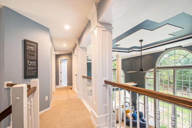 hallway featuring ornamental molding, ornate columns, and light colored carpet