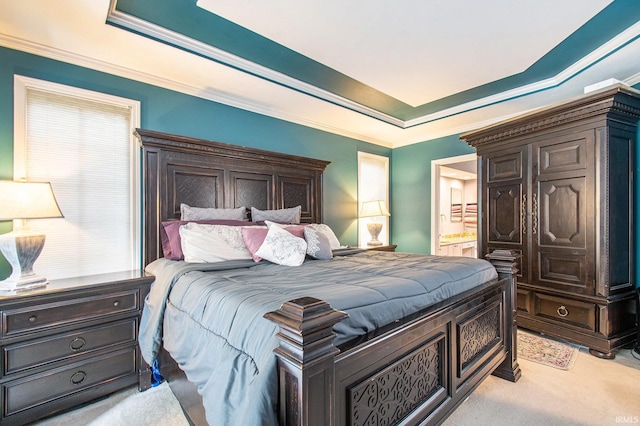 carpeted bedroom featuring crown molding, a raised ceiling, and ensuite bathroom