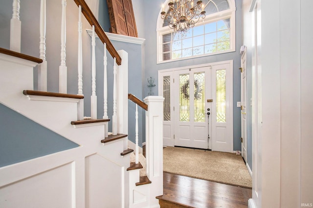 foyer entrance featuring a notable chandelier, wood-type flooring, and a high ceiling