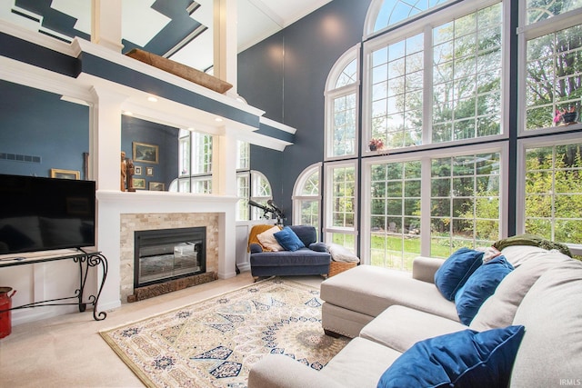 living room featuring a towering ceiling, a wealth of natural light, and ornamental molding