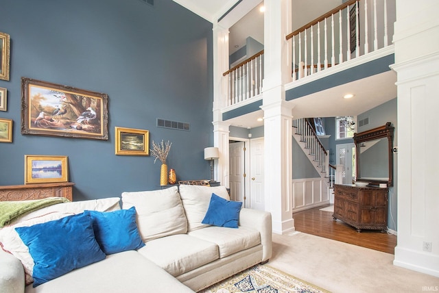 living room featuring ornate columns, a high ceiling, and hardwood / wood-style floors