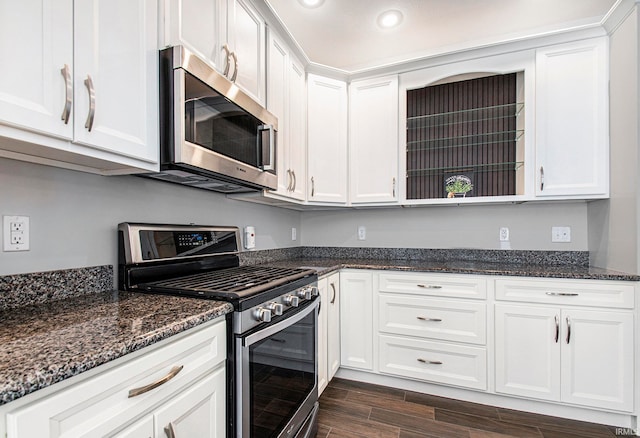 kitchen with white cabinetry, stainless steel appliances, dark stone counters, and dark hardwood / wood-style flooring