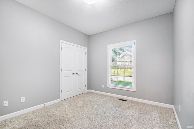 carpeted empty room featuring a textured ceiling