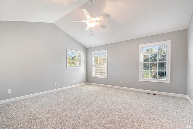 carpeted spare room with ceiling fan, vaulted ceiling, and a wealth of natural light