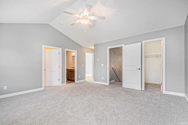 unfurnished bedroom with light carpet, a walk in closet, vaulted ceiling, ensuite bathroom, and ceiling fan