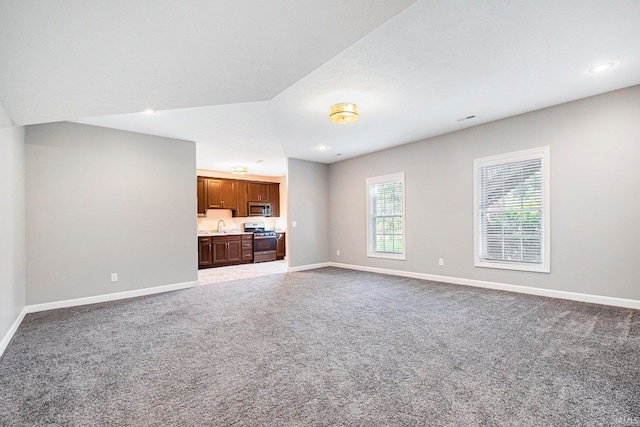 unfurnished living room featuring sink and carpet flooring