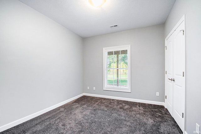 empty room featuring dark colored carpet and a textured ceiling