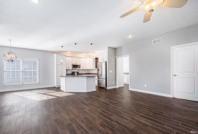 unfurnished living room with sink, dark wood-type flooring, and ceiling fan with notable chandelier