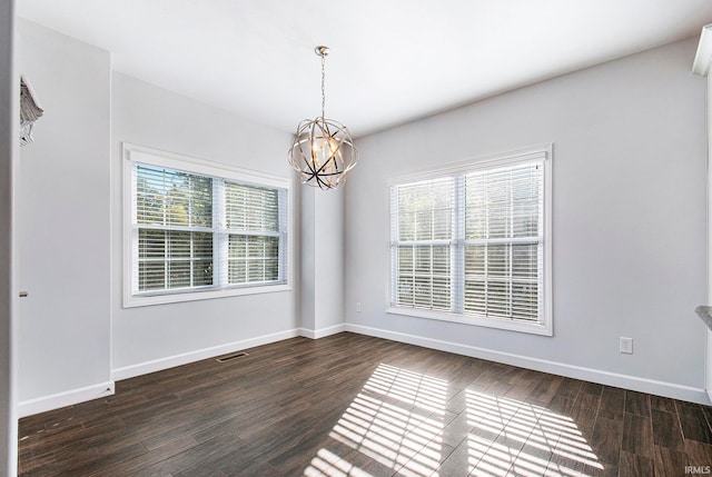 unfurnished room with a notable chandelier and dark hardwood / wood-style floors