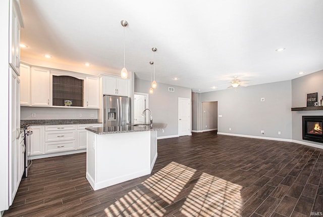 kitchen featuring an island with sink, sink, pendant lighting, appliances with stainless steel finishes, and dark hardwood / wood-style flooring