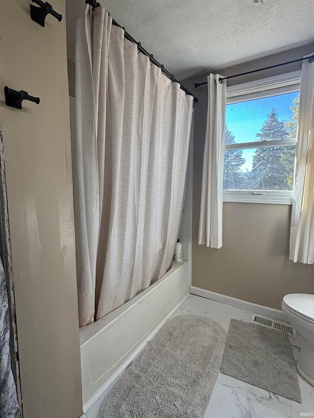 bathroom featuring shower / bath combination with curtain, a textured ceiling, and toilet