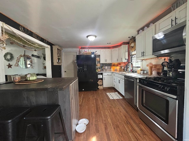 kitchen featuring white cabinets, backsplash, dark hardwood / wood-style floors, sink, and stainless steel appliances