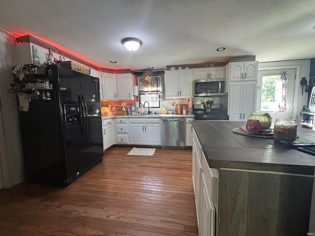 kitchen with decorative backsplash, dark hardwood / wood-style floors, sink, black appliances, and white cabinetry