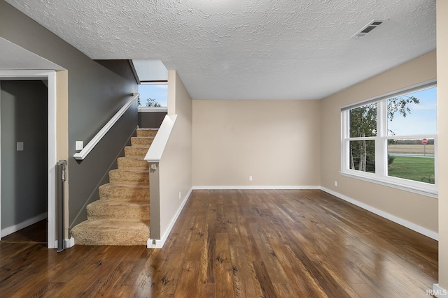 unfurnished living room featuring a textured ceiling and dark hardwood / wood-style flooring