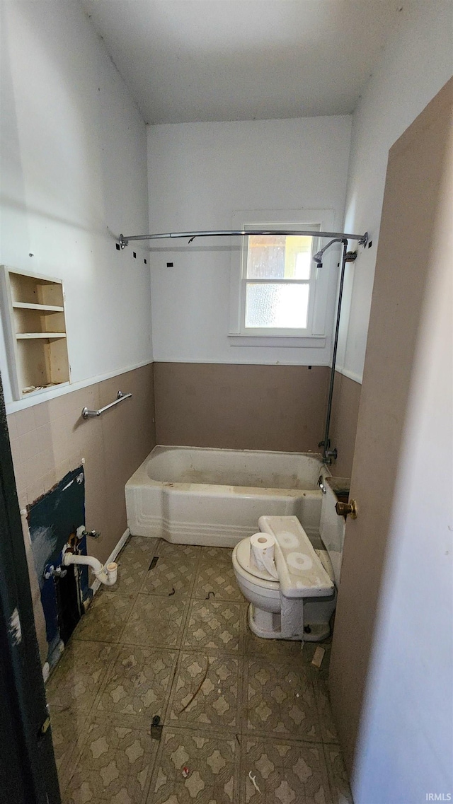 bathroom featuring toilet, a tub, and tile patterned flooring