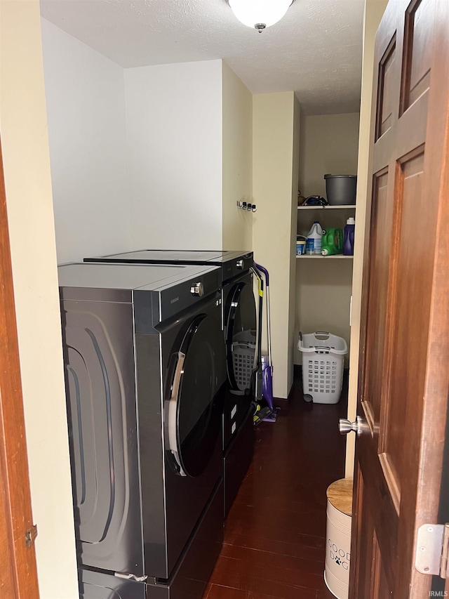 laundry room featuring a textured ceiling, dark wood-type flooring, and washer and clothes dryer