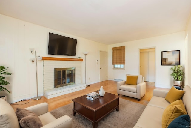 living room featuring a brick fireplace and light wood-type flooring