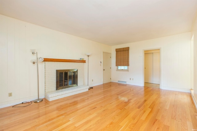 unfurnished living room featuring light hardwood / wood-style floors and a brick fireplace