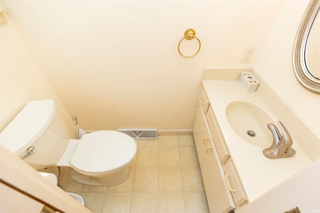 bathroom with toilet, vanity, and tile patterned flooring