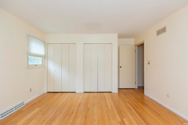 unfurnished bedroom with multiple closets and light hardwood / wood-style floors