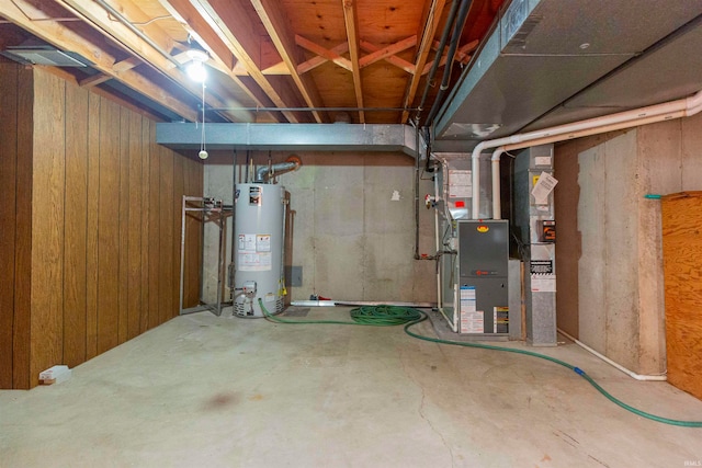 basement with wooden walls, heating unit, and gas water heater