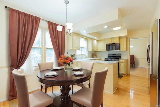 dining space featuring light hardwood / wood-style flooring, sink, a notable chandelier, and plenty of natural light