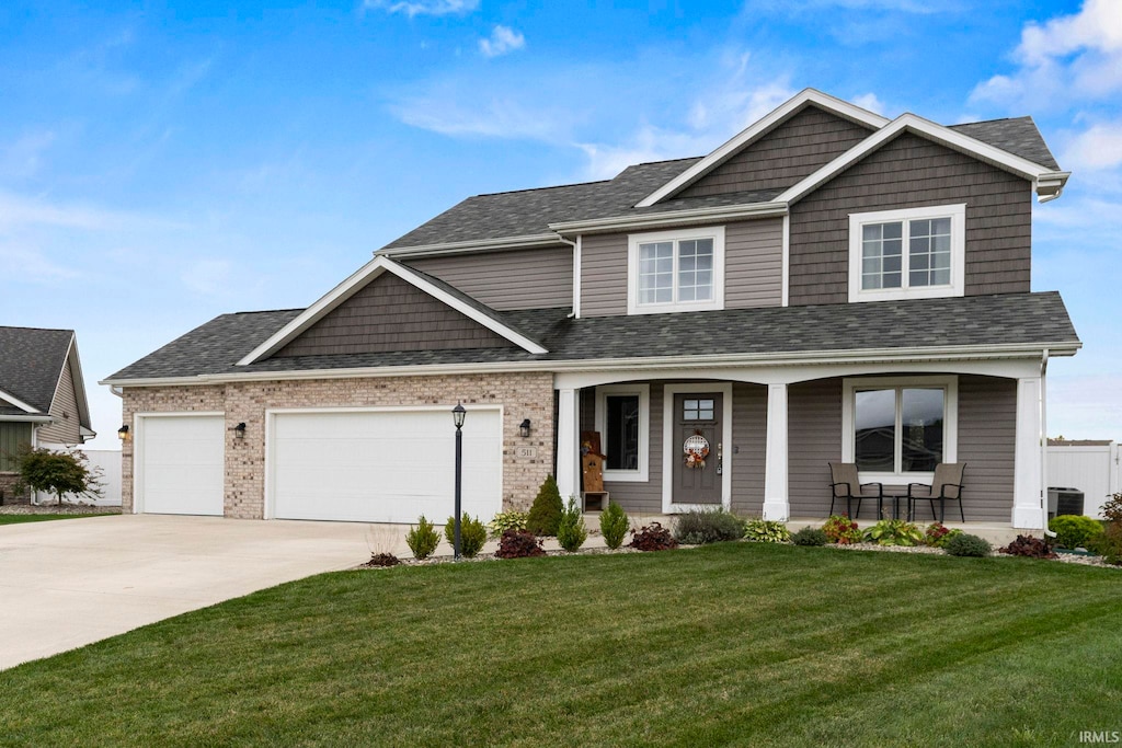 craftsman inspired home with covered porch, a front yard, central AC, and a garage